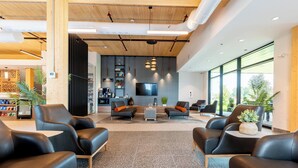 Eine moderne Lobby mit Ledersofas, einem Couchtisch und einem an der Wand befestigten Fernseher.