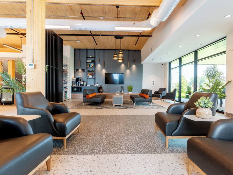 A modern lobby with leather sofas, a coffee table, and a TV mounted on the wall.