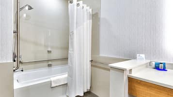 A modern bathroom with a walk-in shower, a bathtub, and a vanity with a towel.