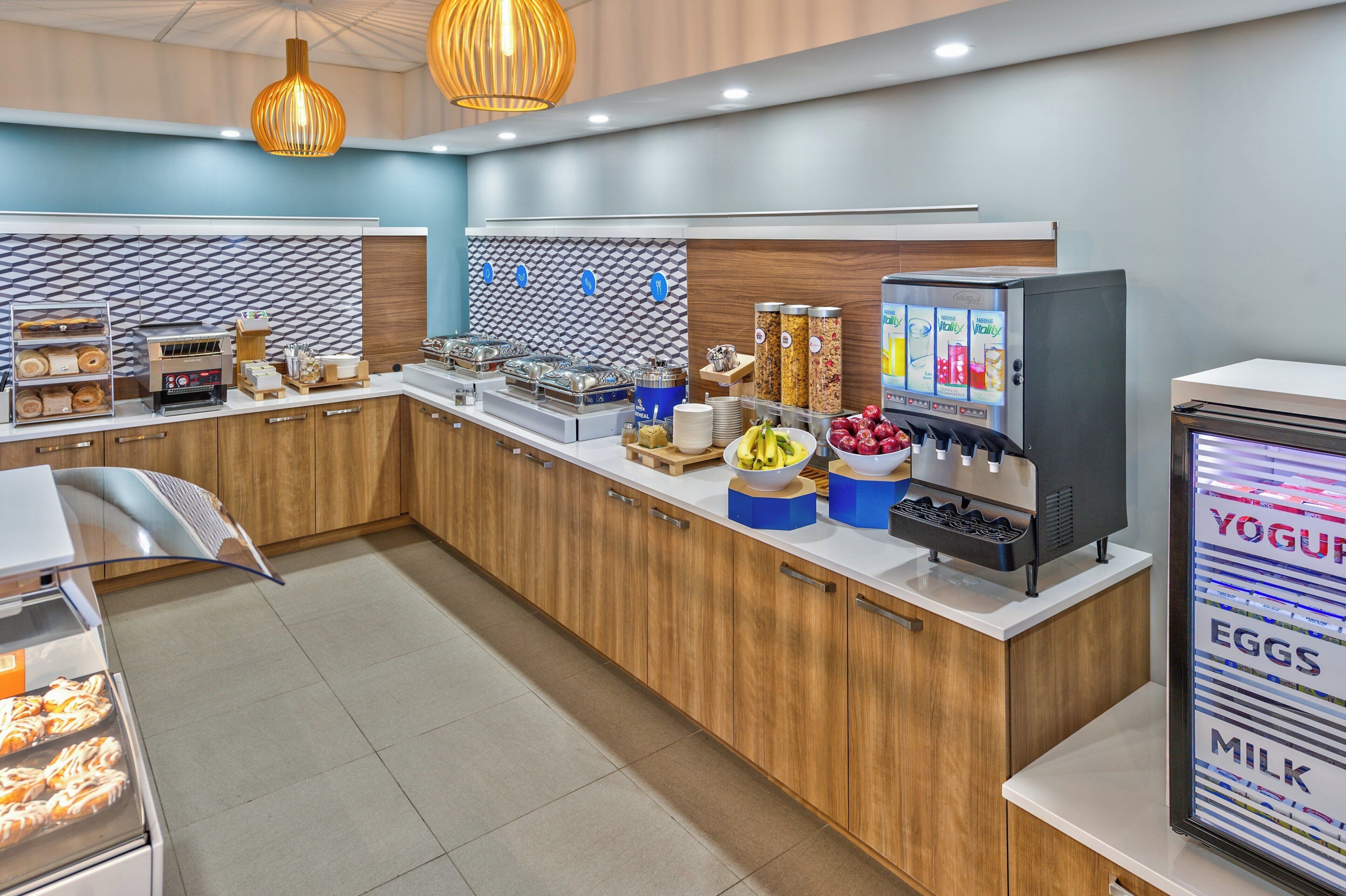 A modern breakfast bar with a variety of food options, including a yogurt machine and a display of eggs and milk.