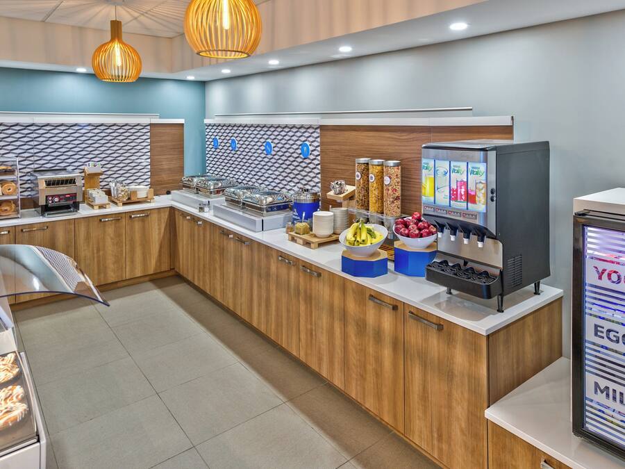 A modern breakfast bar with a variety of food options, including a yogurt machine and a display of eggs and milk.