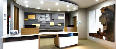 Uma receção com design moderno, um grande quadro abstrato na parede e uma placa com o nome do hotel.