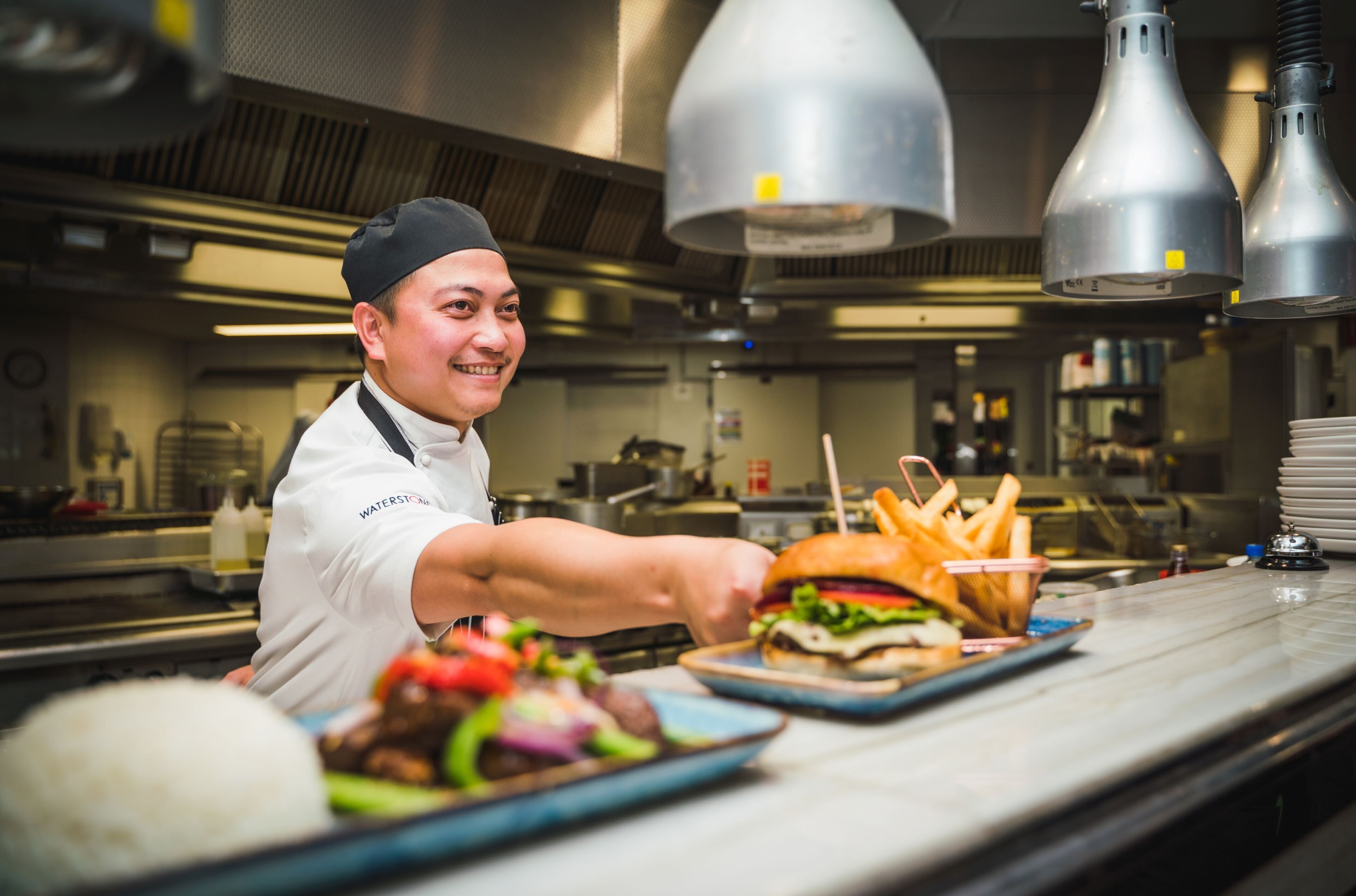 A chef in a professional kitchen with stainless steel appliances and a clean, organized workspace.