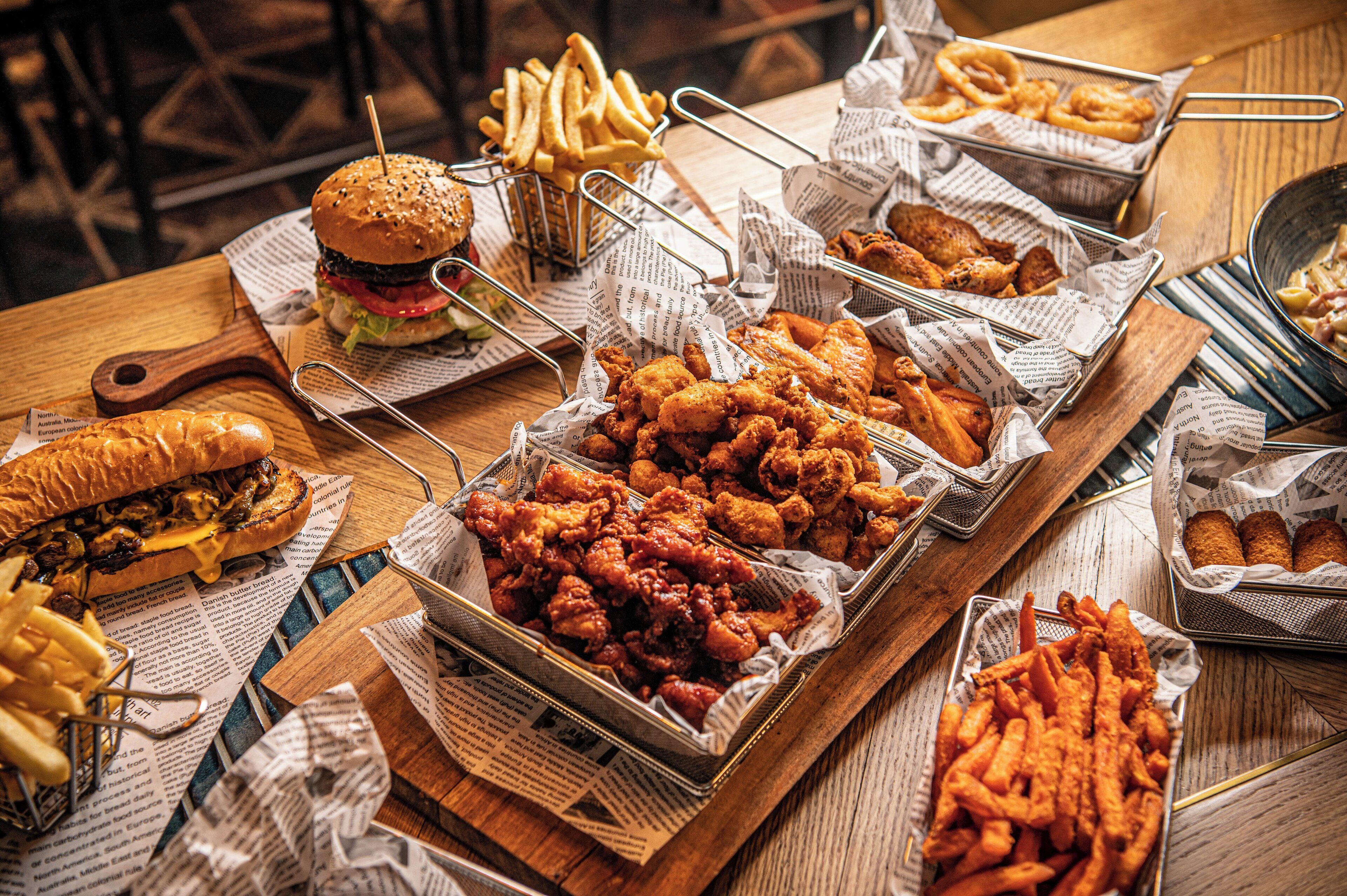 A buffet table with various food items including burgers, fried chicken, and French fries.
