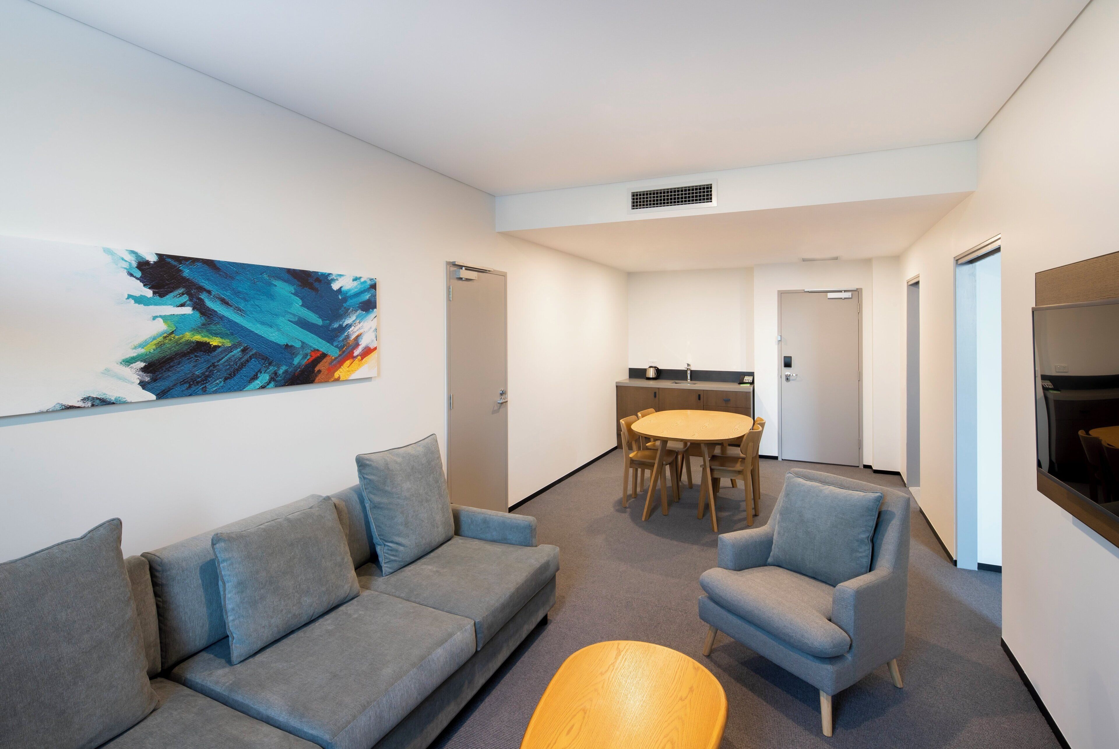Un interior moderno con un sofá gris, una mesa redonda y un sillón azul.