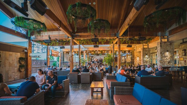 An outdoor seating area with wicker furniture, stone walls, and hanging greenery. - Holiday Inn Sydney St Marys by IHG (North St Marys)