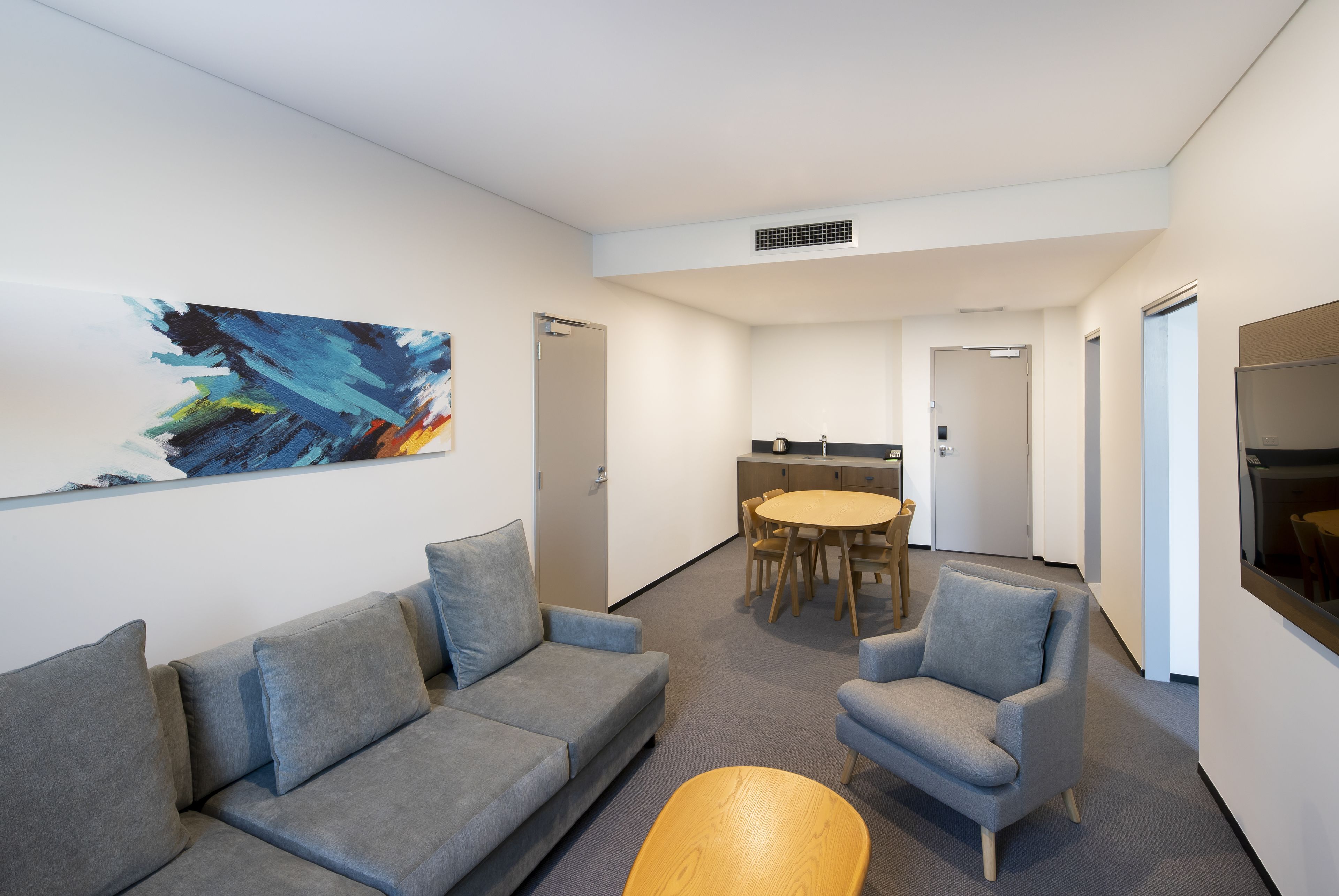 A modern interior with a grey sofa, a round table, and a grey armchair.