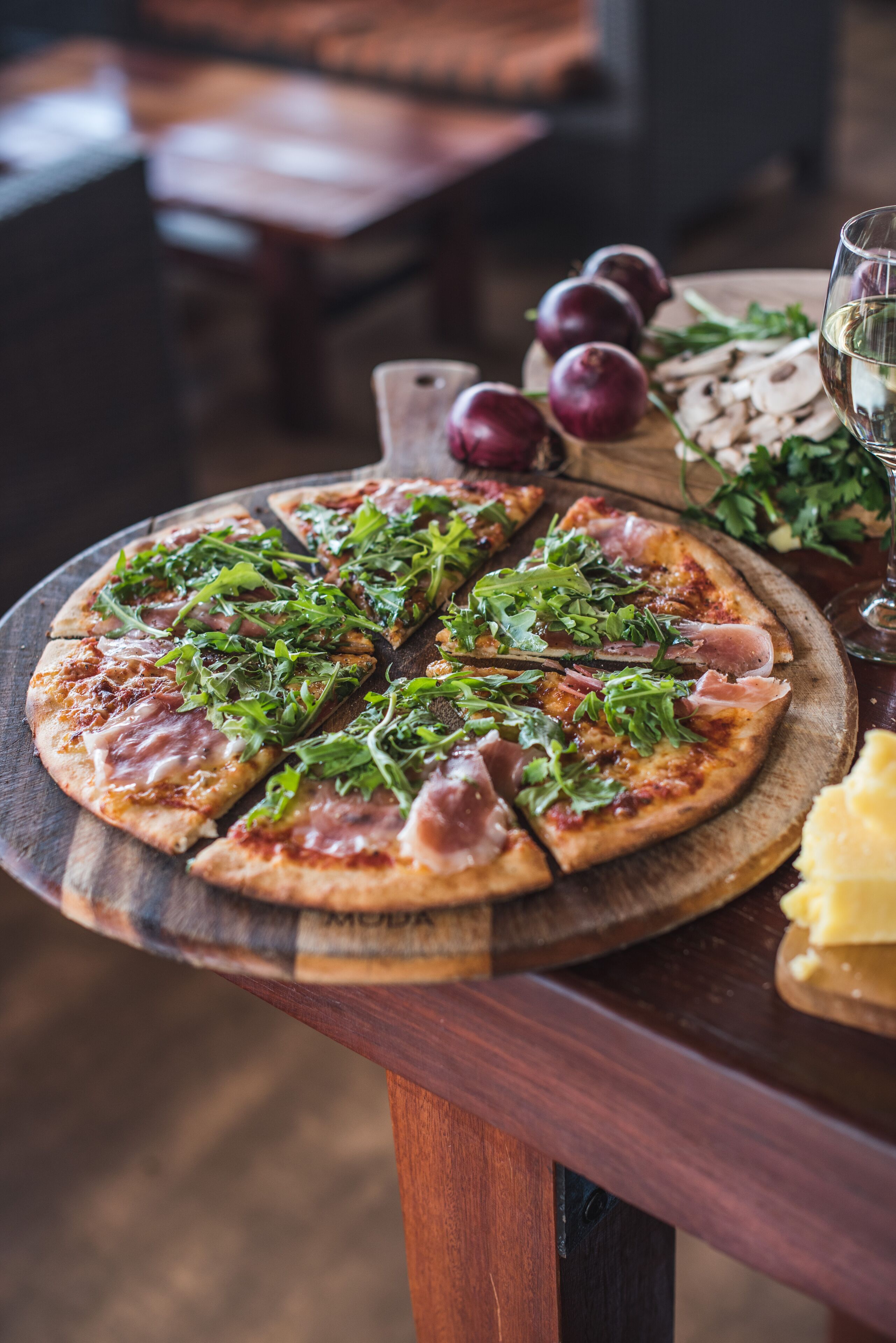 Pizza met rucola en parmaham op een houten plank.