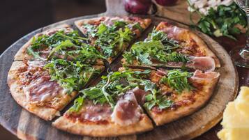 Pizza met rucola en parmaham op een houten plank.