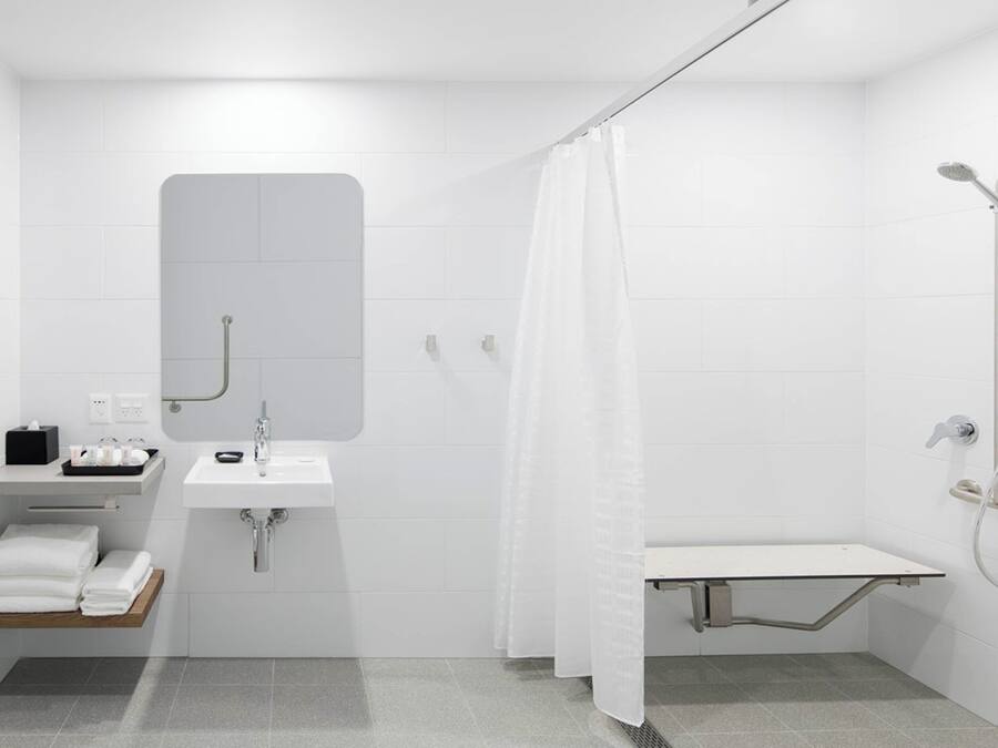 A modern bathroom with a sink, mirror, shower, and towel rack.