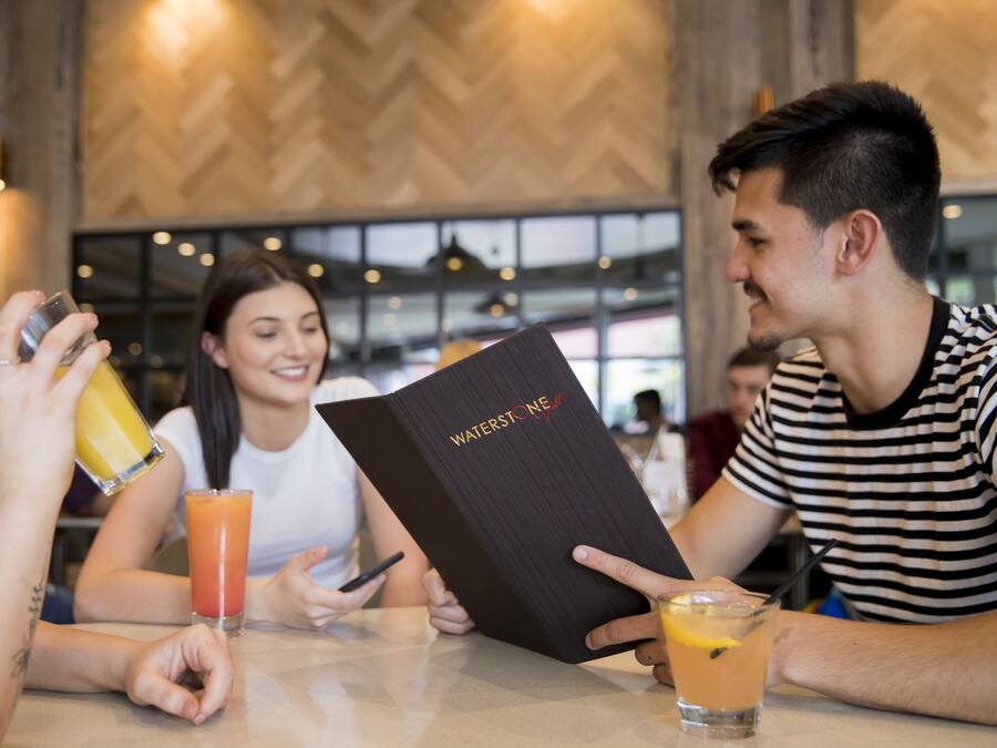 Um grupo de pessoas sentadas à mesa num restaurante com design de interiores moderno, incluindo padrão de madeira em espinha de peixe nas paredes e iluminação pendente.