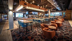 A modern bar with multiple seating areas, including bar stools and tables, and a patterned floor. - Holiday Inn Sydney St Marys by IHG (North St Marys)