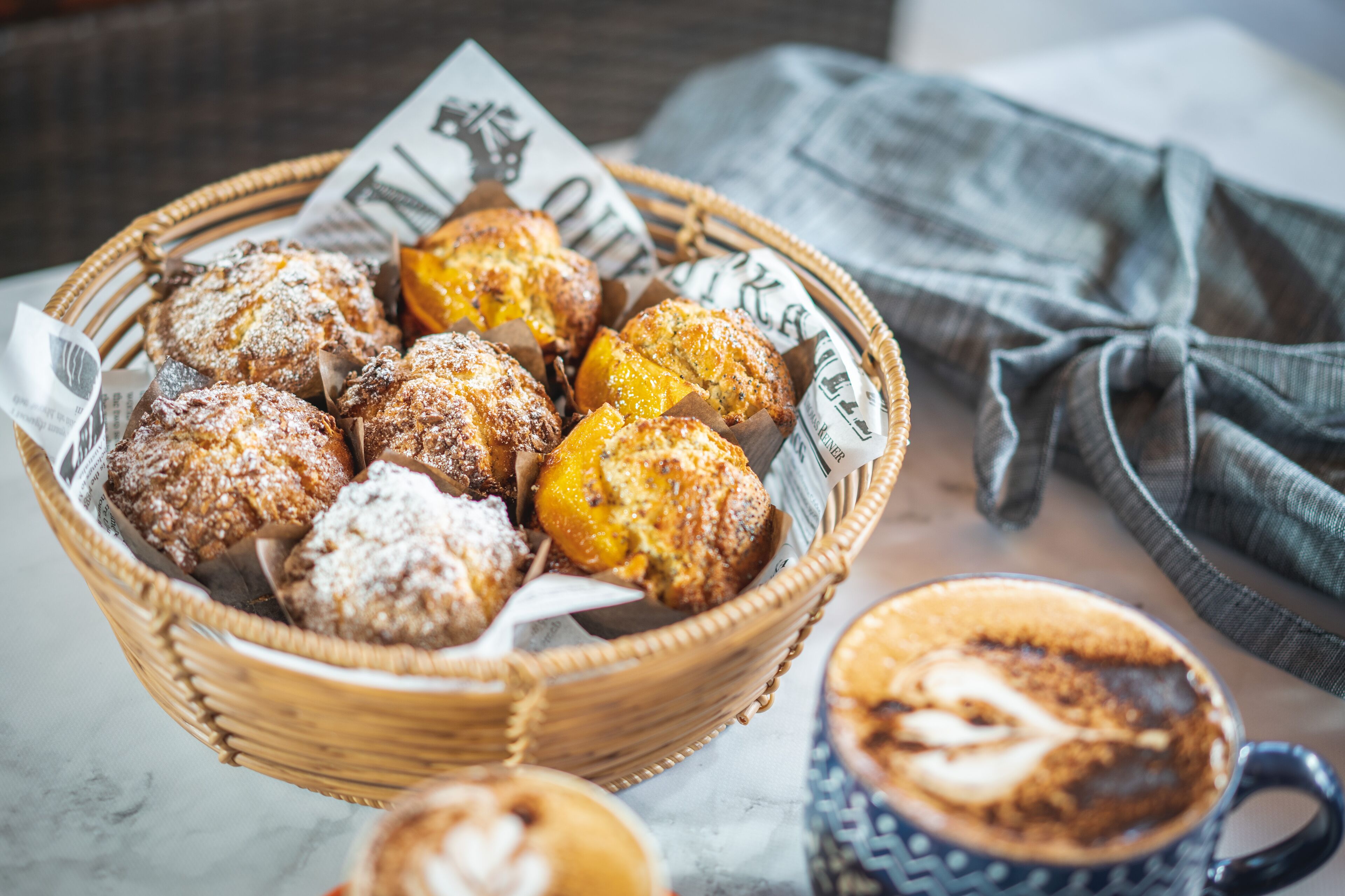 Una cesta de pasteles y una taza de café sobre una mesa.