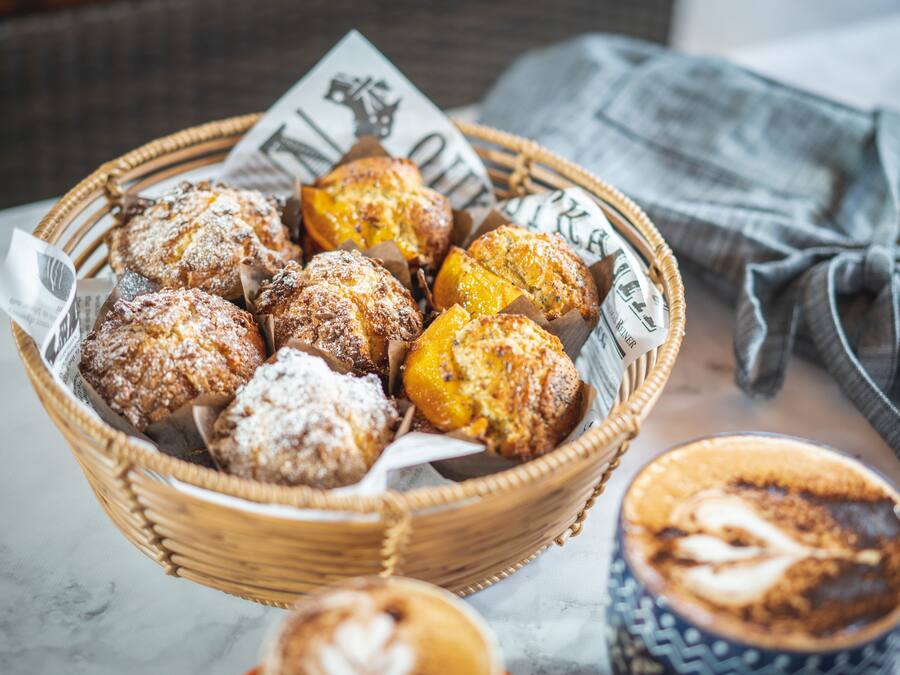 A basket of pastries and a cup of coffee on a table.