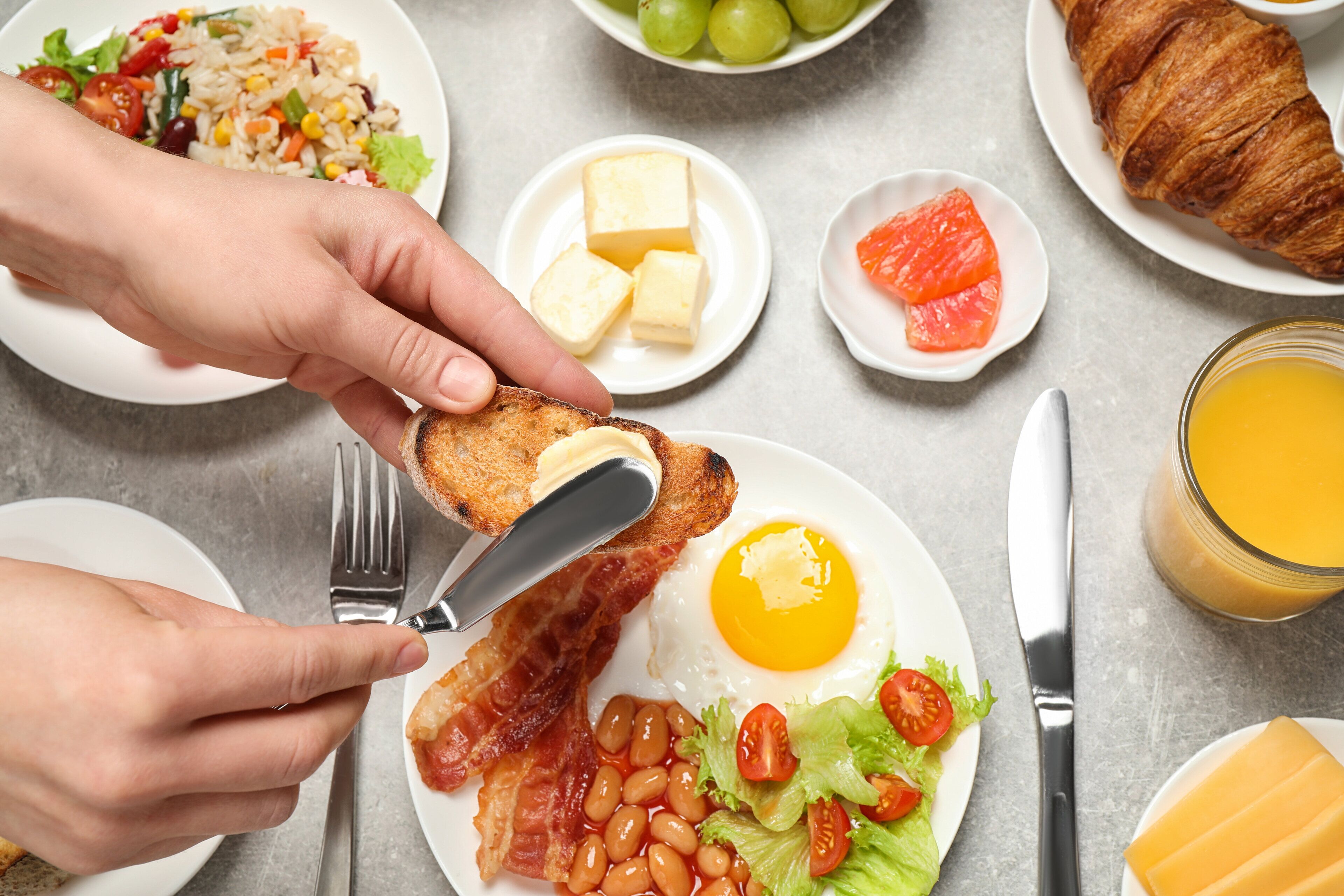 Une table dressée pour le petit-déjeuner avec des toasts, des œufs, du bacon, des haricots et une salade dans une assiette.