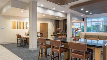 A modern interior with a central dining area, a reception desk, and a seating area with a view.