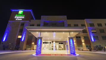 A Holiday Inn Express & Suites hotel entrance with a covered driveway and illuminated signage.
