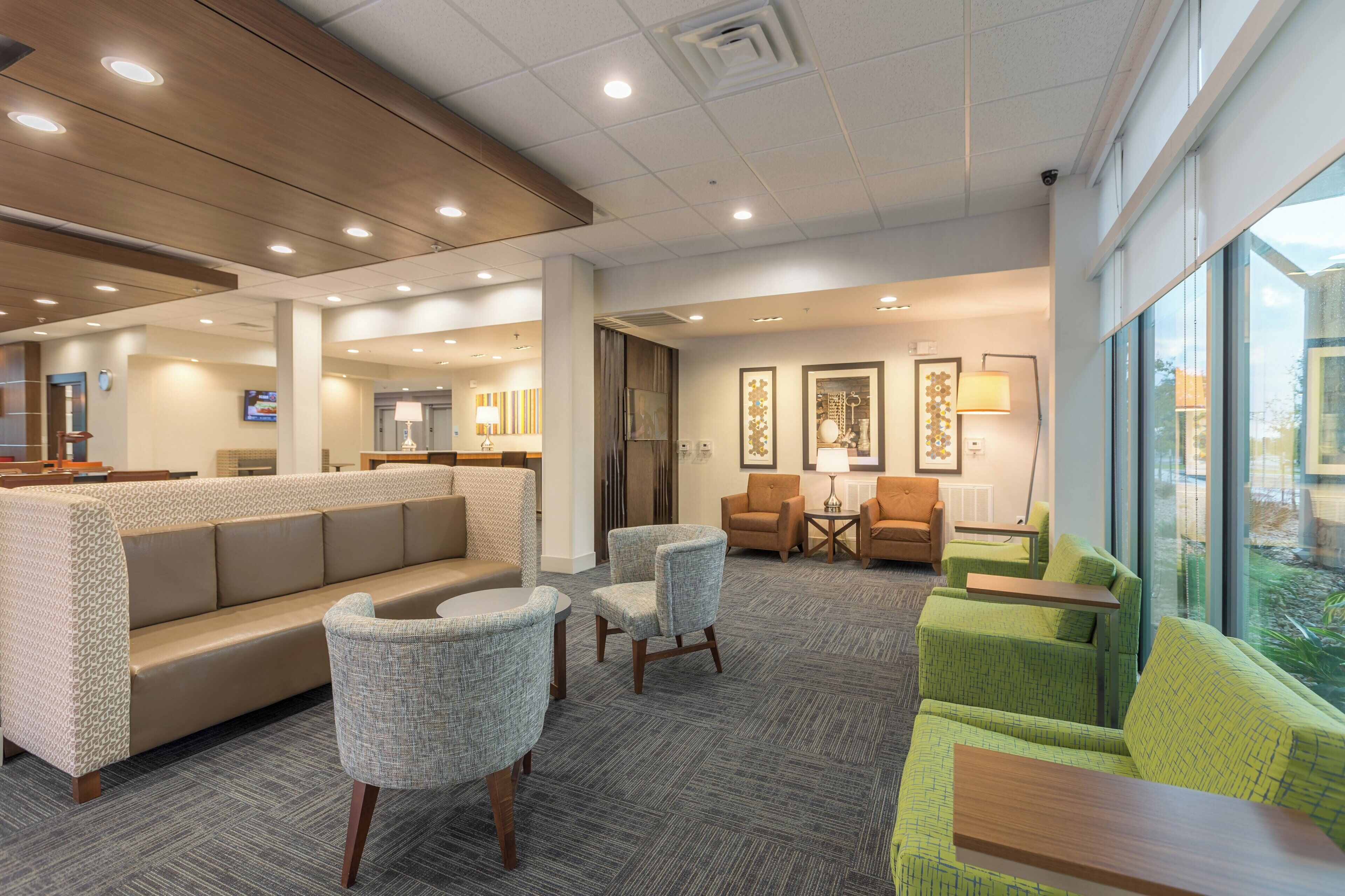 A hotel lobby with a reception desk, seating area, and large windows.