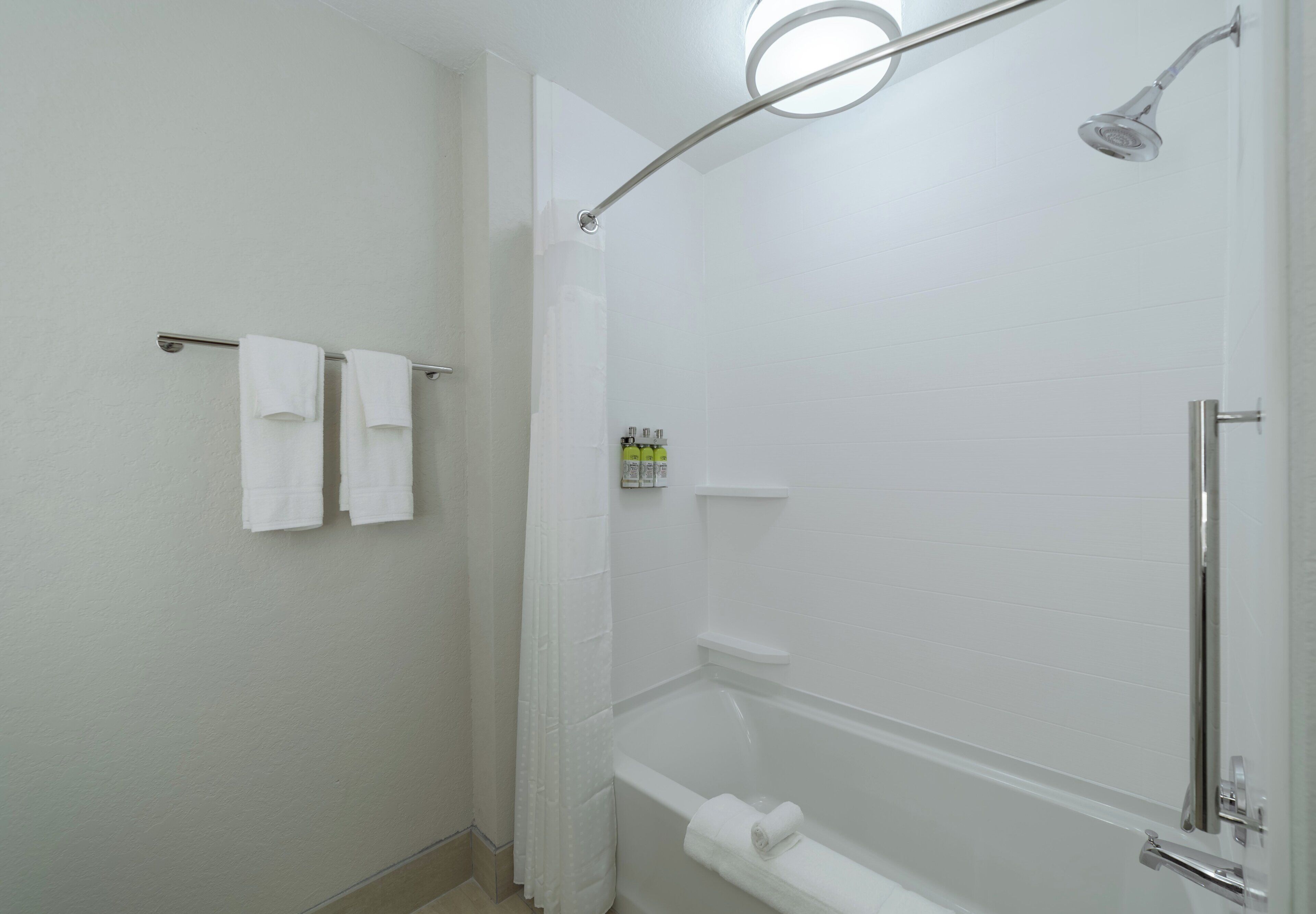 A bathroom with a shower, a bathtub, and a towel rack with two towels.