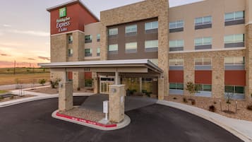 A Holiday Inn Express & Suites building with a stone facade, large windows, and a covered entrance.