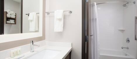 A modern bathroom with a sink, mirror, towel rack, shower, and toilet.