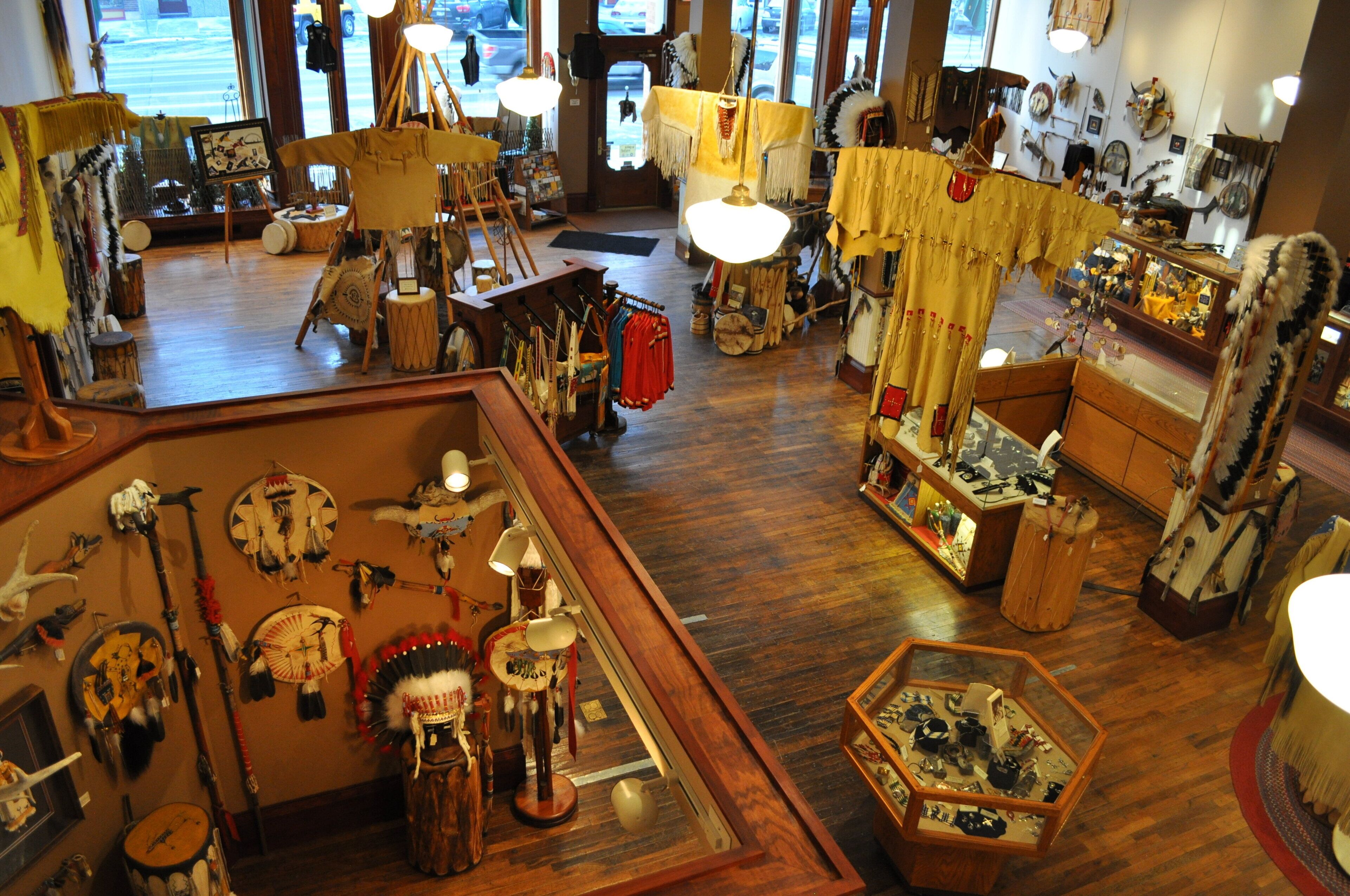 A room with wooden flooring, various Native American artifacts, and a large window.