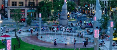 Una plaza pública con una fuente central, zonas de descanso y edificios circundantes.
