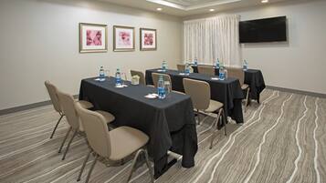 A conference room with tables, chairs, water bottles, and framed pictures on the wall.