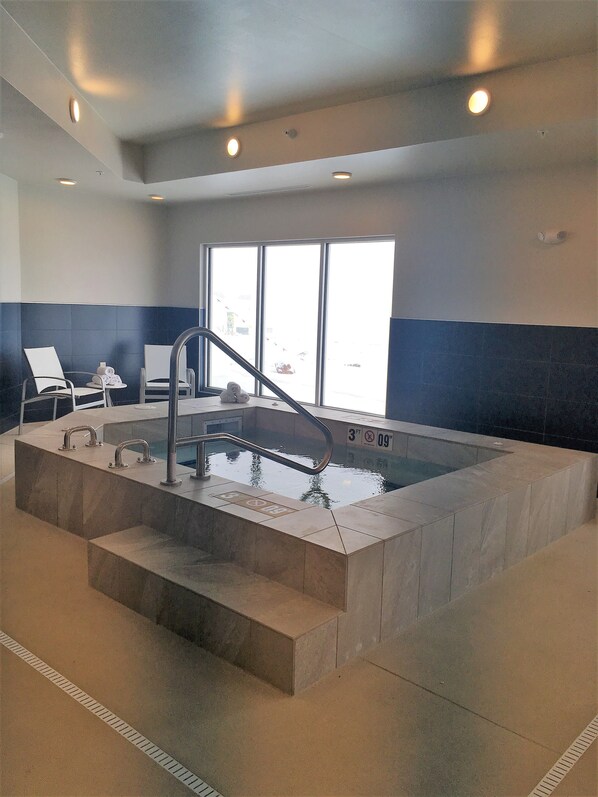 Una piscina interior con una profundidad de 90 centímetros, un vestuario con sillas y vistas al exterior.