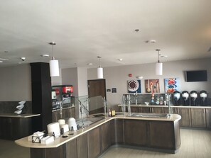 Une cuisine moderne dotée d’un îlot central, d’un réfrigérateur Coca-Cola et d’un espace dédié à la préparation du café.