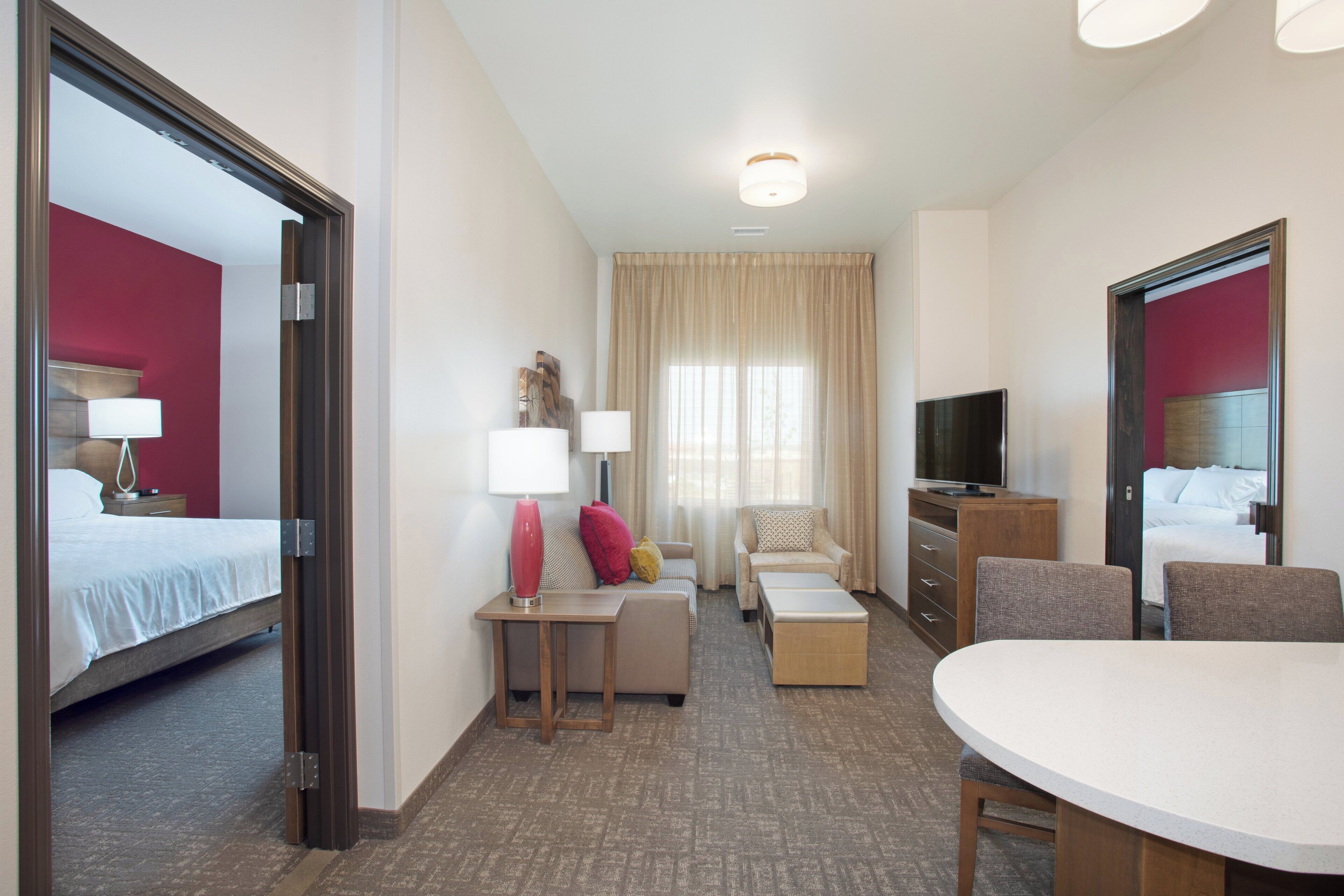 Una habitación de hotel con una cama, un sofá, una mesa de centro, un televisor y una mesa de comedor.