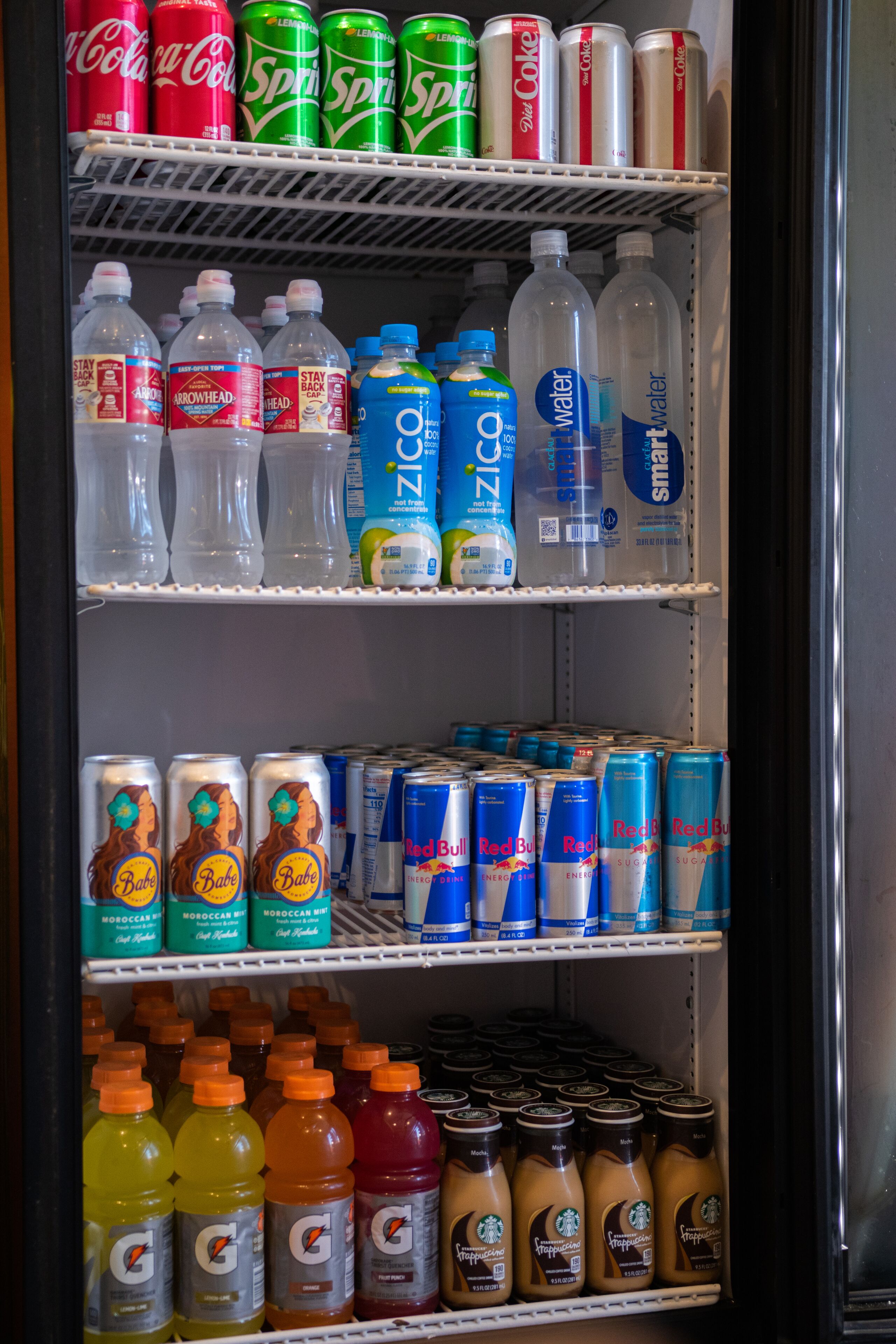 Un refrigerador para bebidas repleto de varias opciones, como gaseosas, agua y bebidas energéticas.