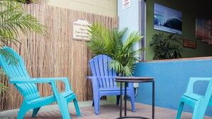 A patio area with two turquoise chairs, a small round table, and a bamboo fence. - California Dreams Hostel - Pacific Beach (San Diego)