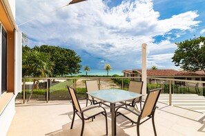 A balcony with a glass table and chairs, overlooking a beach and palm trees. - Casa Grande by Playa Paradise (Playa del Carmen)