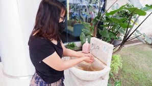A person washing hands at a stone sink outdoors. - News Front One Hotel Surabaya (Sidoarjo)