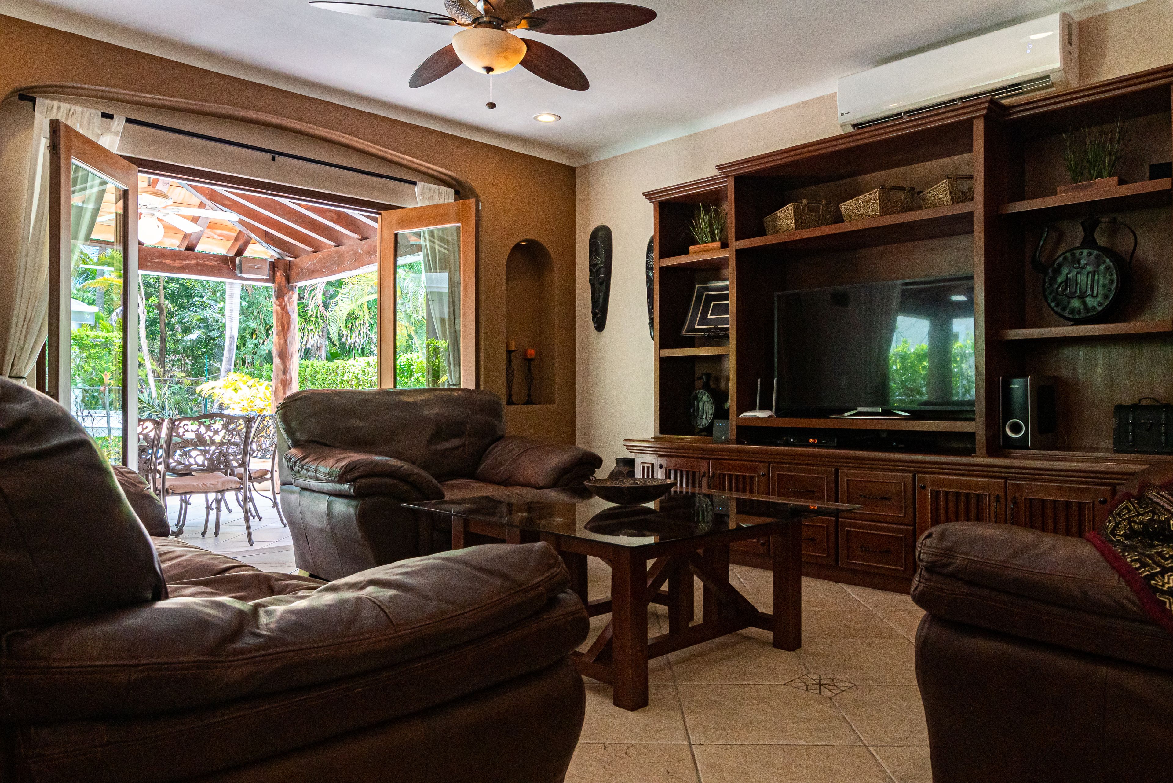 A living room with leather sofas, a coffee table, a TV, and wooden shelves.