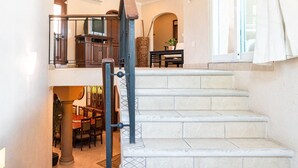 Una escalera con barandilla de metal que lleva a una zona en el segundo piso, con una mesa y sillas.
