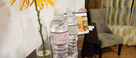 A table with a vase of yellow flowers, two water bottles, and a glass of water.