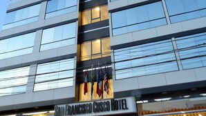 A modern hotel building with multiple floors, large windows, and flags at the entrance. - San Francisco Cusco Hotel (Cusco)