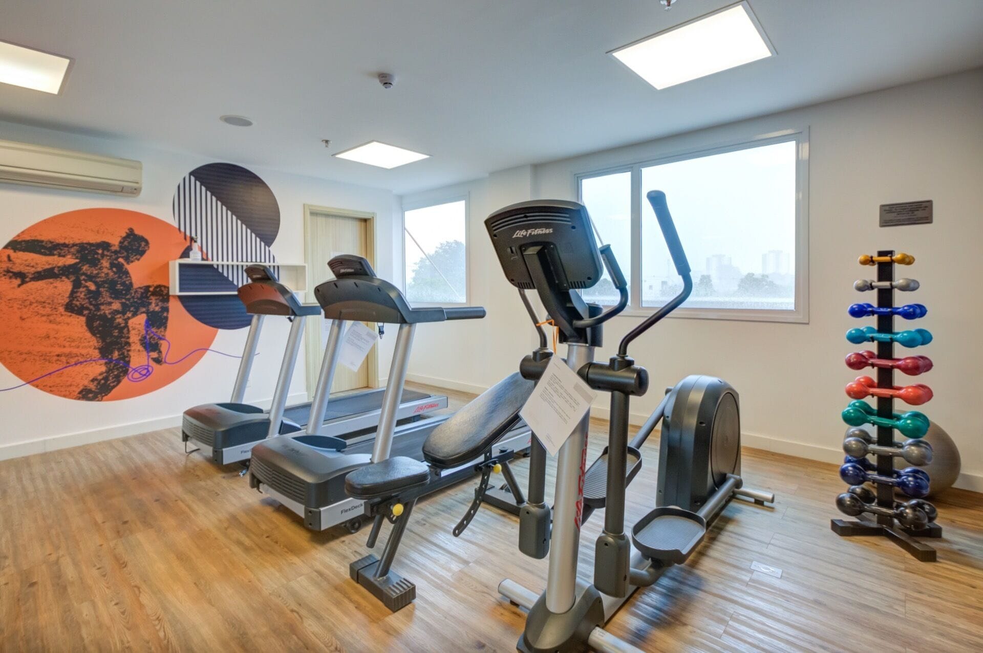 Un gimnasio con cintas de correr, elíptica y un soporte para pesas.