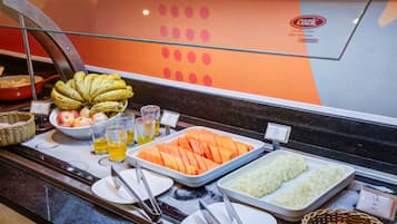 A buffet with various food items including bananas, apples, carrots, and potatoes.