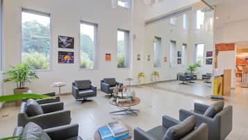 A spacious lobby with multiple seating areas, large windows, and artwork on the walls.