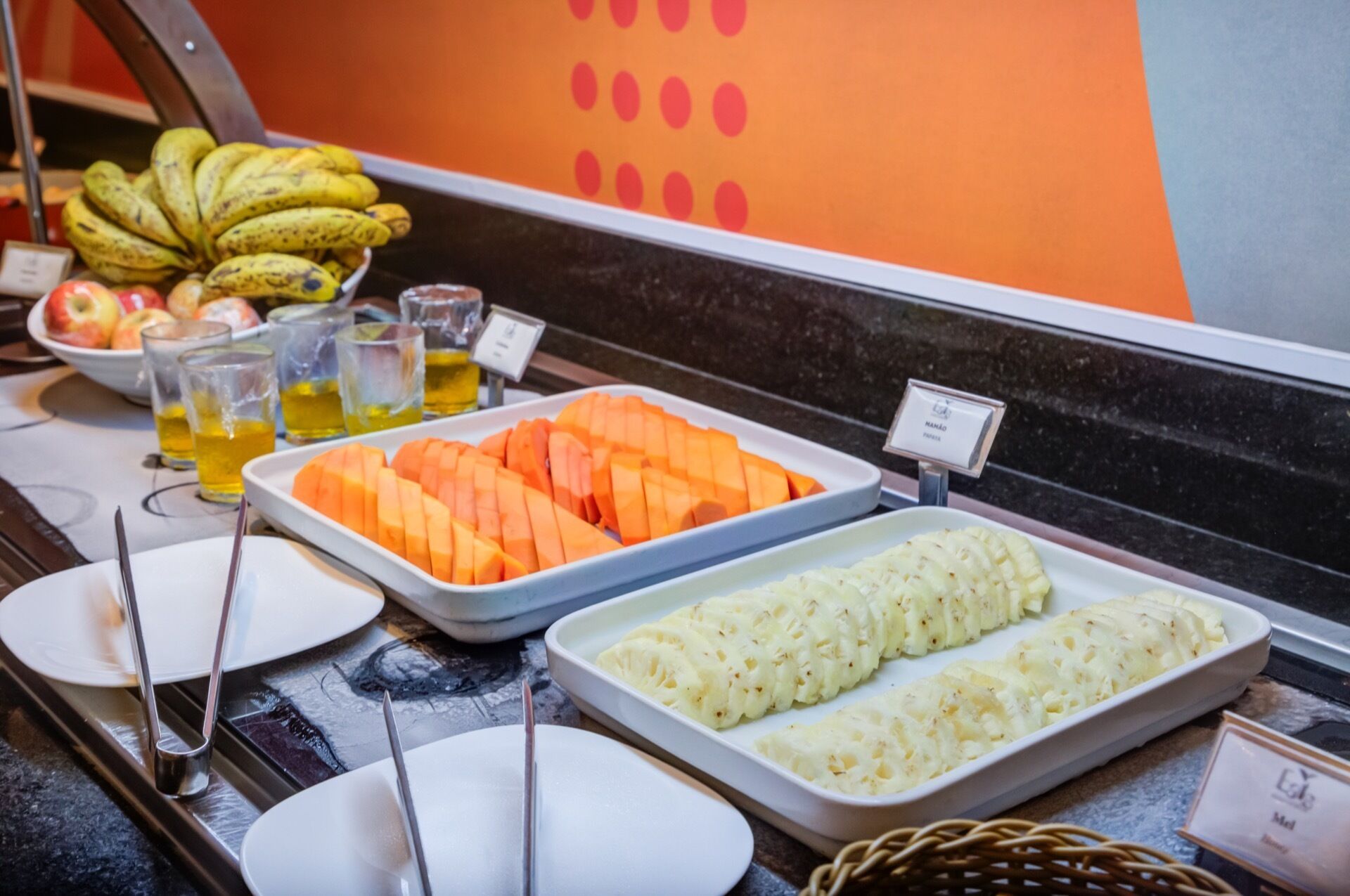 Un bufé con diferentes opciones de comida, entre ellas frutas y verduras cortadas, y un cartel que indica el precio.