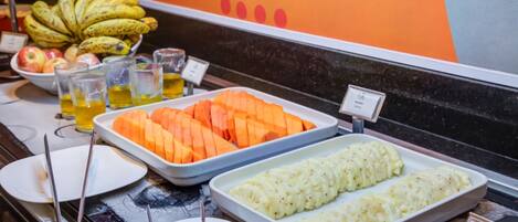 A buffet with various food items including sliced fruits and vegetables, and a sign indicating the price.