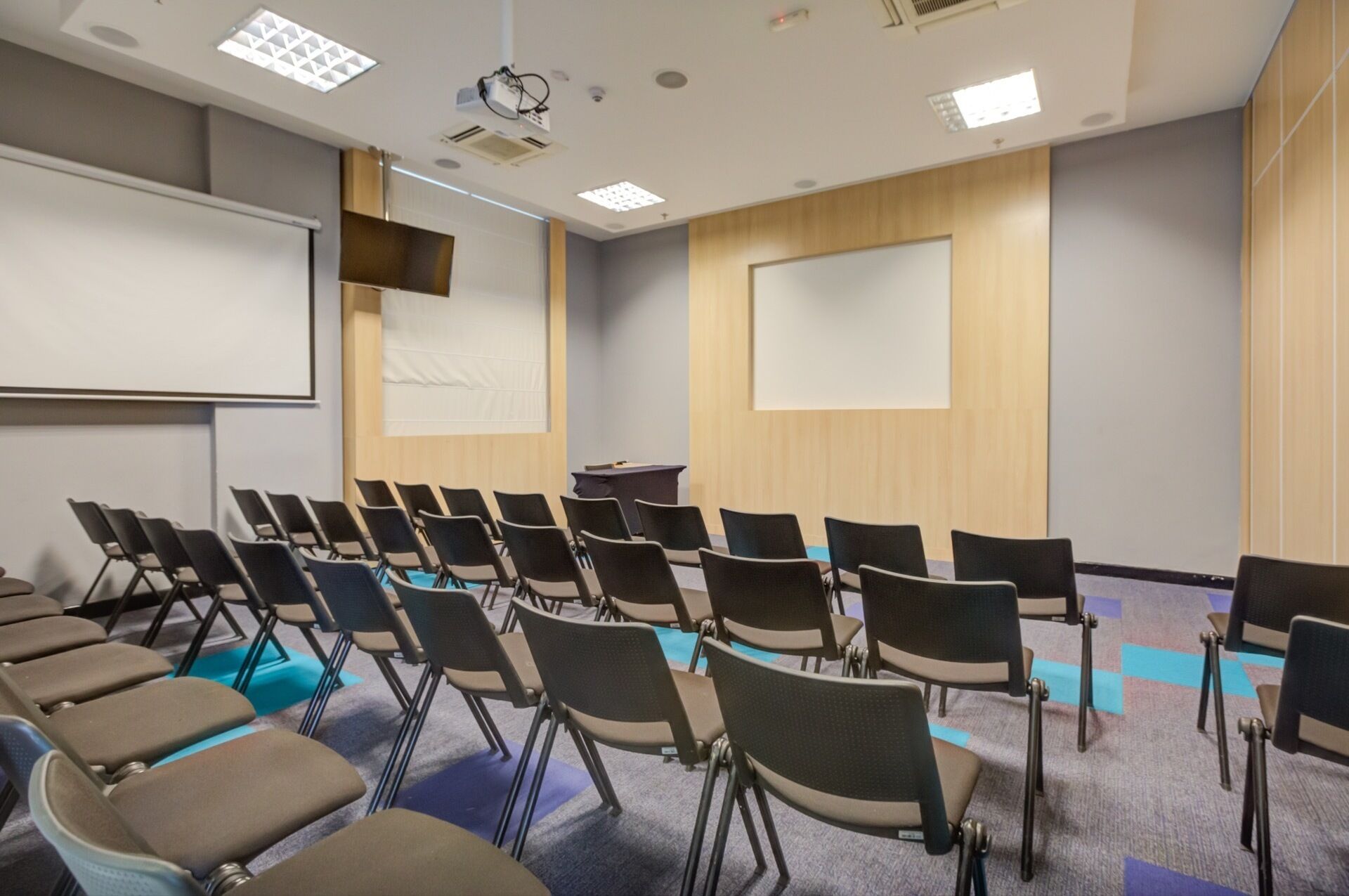 A conference room with rows of chairs, a projector screen, and a large whiteboard.