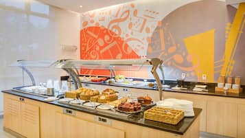 A buffet area with various food items and a decorative wall with abstract designs.