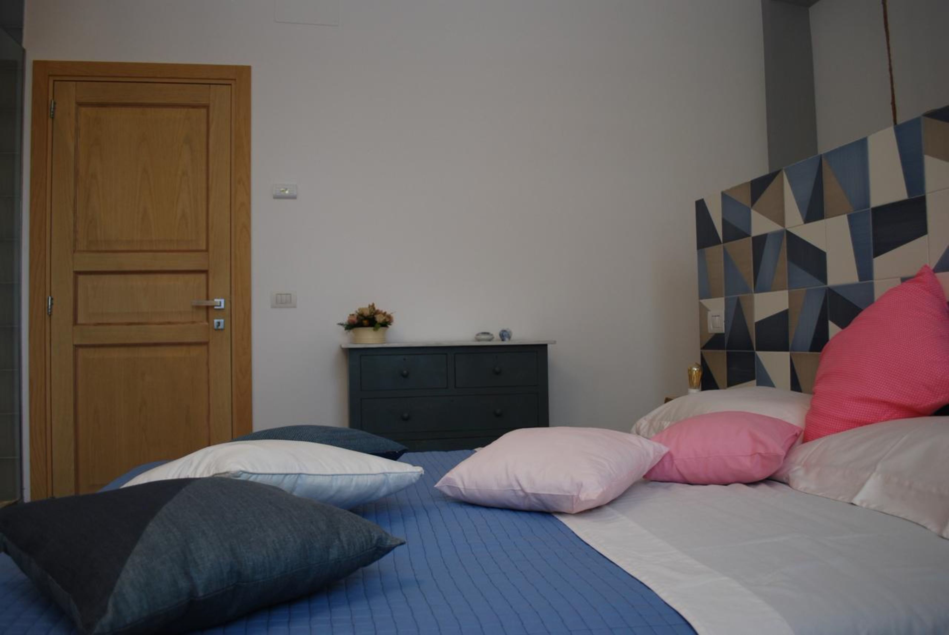Ein Schlafzimmer mit einem Bett, Kissen, einem Schminktisch und einer Holztür.
