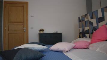 Ein Schlafzimmer mit einem Bett, Kissen, einem Schminktisch und einer Holztür.