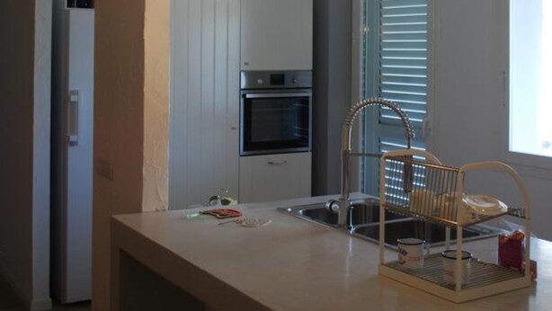 Una cocina moderna con una isla central, lámparas colgantes y vistas al área de comedor contigua.