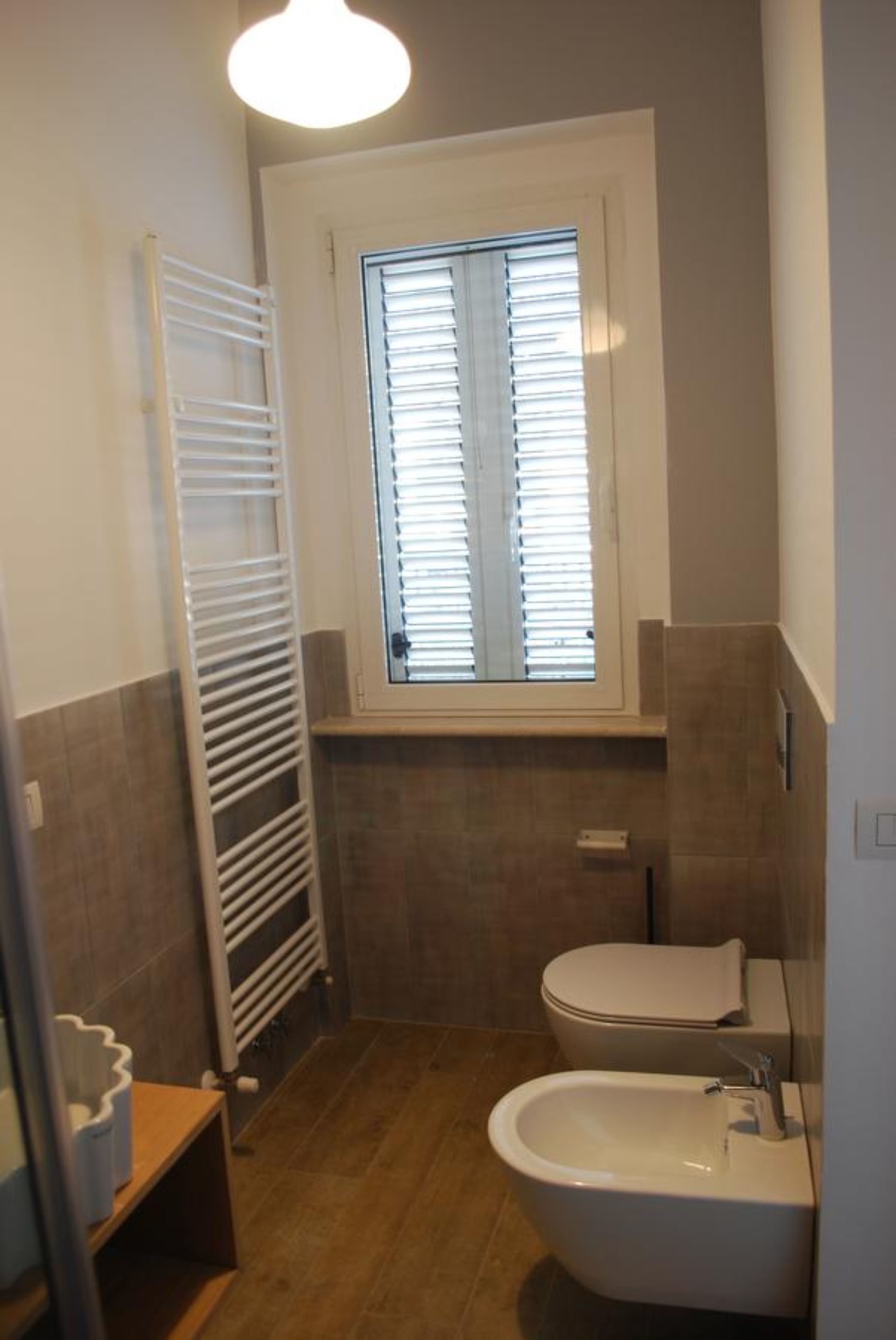 Ein kleines Badezimmer mit Toilette, Bidet und Handtuchhalter.
